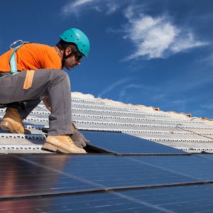 Technician installing solar panels on a home roof under a clear sky in Atlanta, GA 