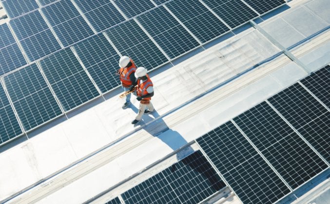 Technician installing solar panels on a commercial building in Atlanta, GA
