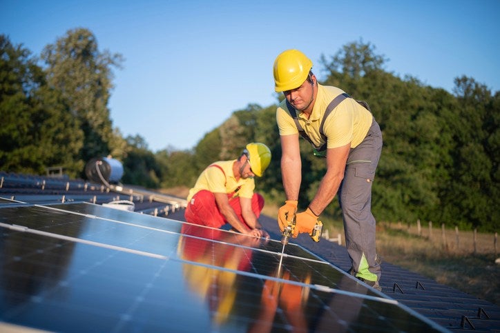 Two workers installing solar panels outdoors on a sunny day in Atlanta, GA