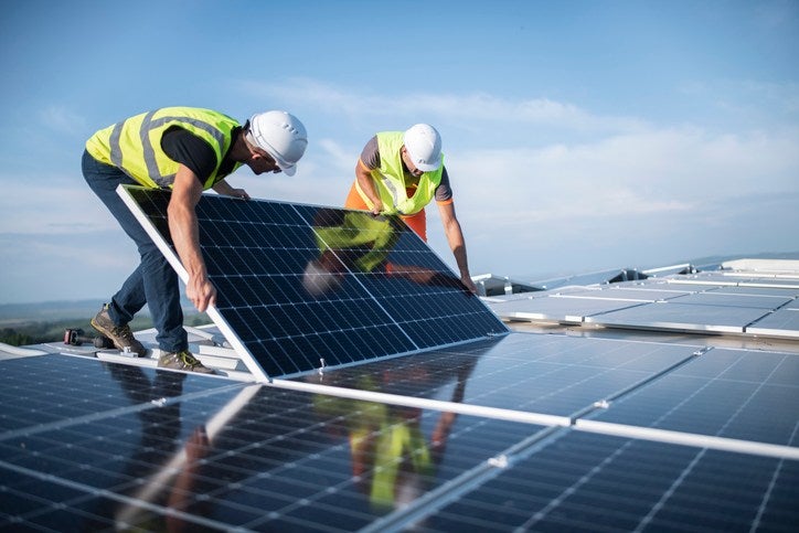 Two workers installing solar panels outdoors on a sunny day in Atlanta, GA
